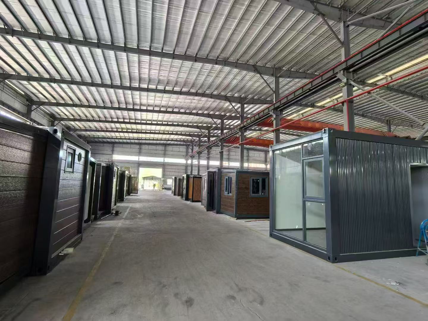 Completed expandable container houses folded and prepared for shipping container loading