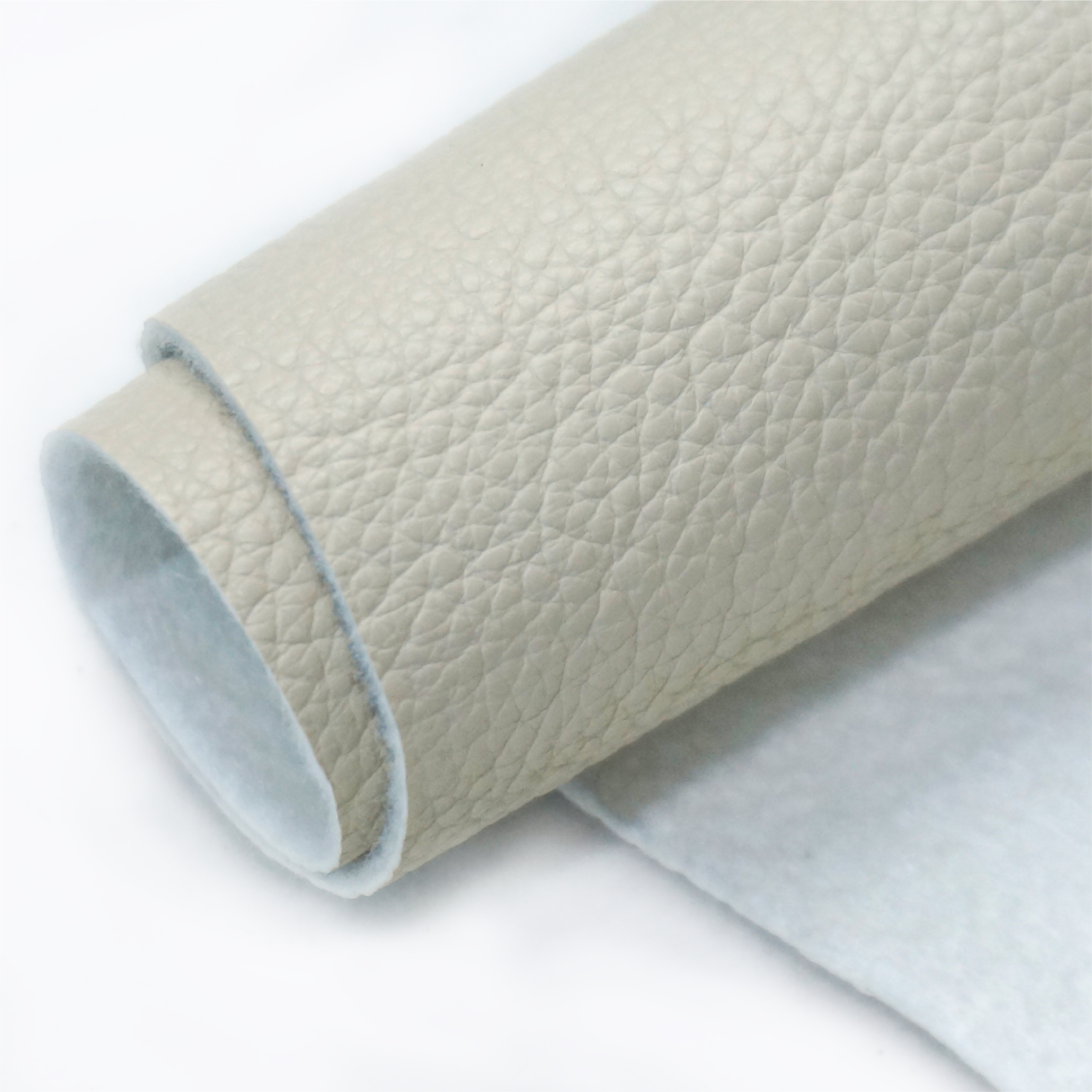 Eco-friendly synthetic leather sample rolls showing various textures and backing options for furniture and bags